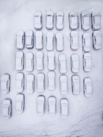 Aerial top down view of a city parking lot with many cars covered in fresh snowの写真素材