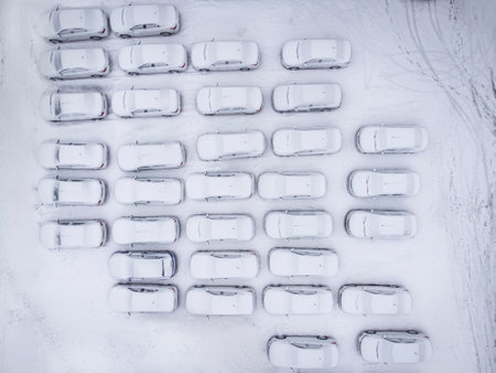 Aerial top down view of a city parking lot with many cars covered in fresh snowの写真素材