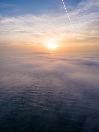 Aerial view of a sunrise sea with a blanket of morning fog and morning sunbeams shining throughの写真素材