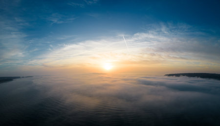 Aerial view of a sunrise sea with a blanket of morning fog and morning sunbeams shining throughの写真素材
