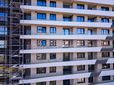 Drone flight along the facade of a modern apartment building under construction surrounded by scaffoldingの写真素材