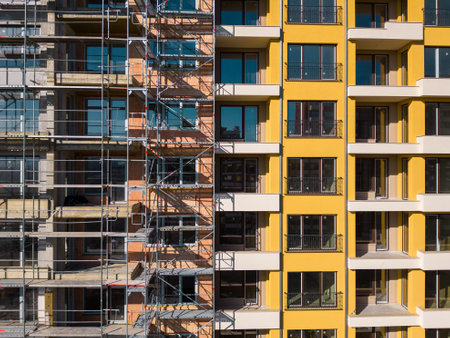 Drone flight along the facade of a modern apartment building under construction surrounded by scaffoldingの写真素材