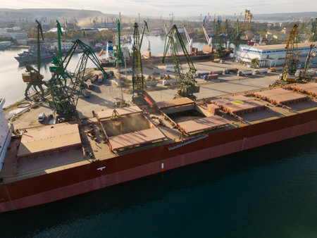 Aerial view of big cargo ship bulk carrier is loaded with grain of wheat in port at sunset.の写真素材