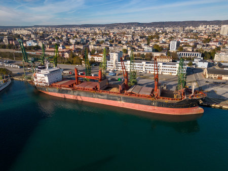 Aerial view of big cargo ship bulk carrier is loaded with grain of wheat in port at sunset.の写真素材