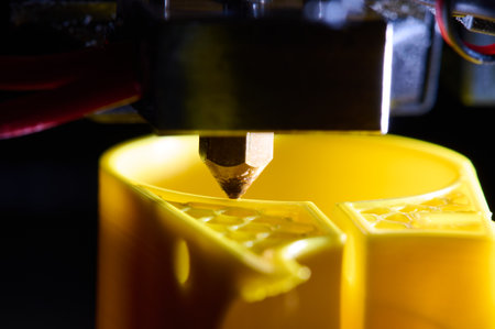 3D printer printing a part made of yellow plastic, close-up viewの写真素材