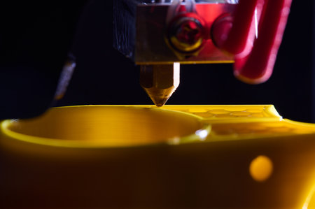 3D printer printing a part made of yellow plastic, close-up viewの写真素材