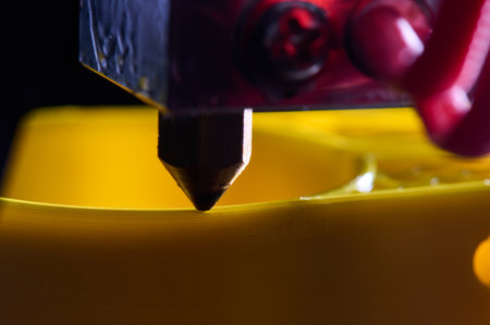 3D printer printing a part made of yellow plastic, close-up viewの写真素材