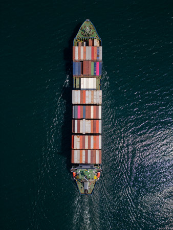 A container ship moves steadily through the ocean, carrying stacked containers