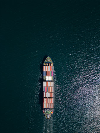 A container ship moves steadily through the ocean, carrying stacked containers