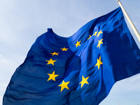 A close-up shot of the European Union flag waving in the wind, with its iconic blue background and golden stars. The movement of the fabric adds a dynamic and patriotic feelの写真素材