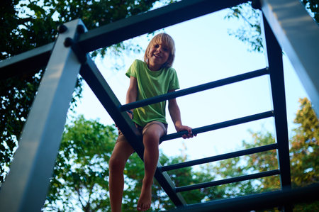 A young boy climbing on a jungle gym during a sunny afternoon in a local park, experiencing joy and adventure in natureの写真素材