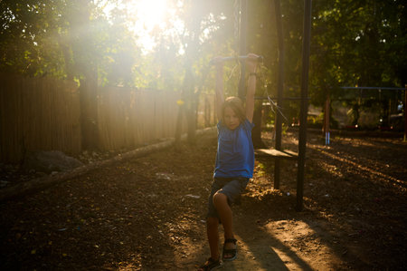 Child joyfully swinging on a playground swing during golden hour in a quiet park setting