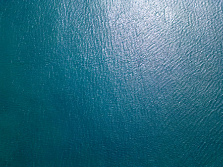 Aerial view of calm, deep blue ocean water with gentle ripples and natural sunlight reflections. Ideal for background textures, nature themes, or tranquil seascape visualsの写真素材