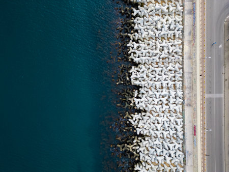 Heavy concrete tetrapods lined along the shoreline at a coastal area during daylight hoursの写真素材