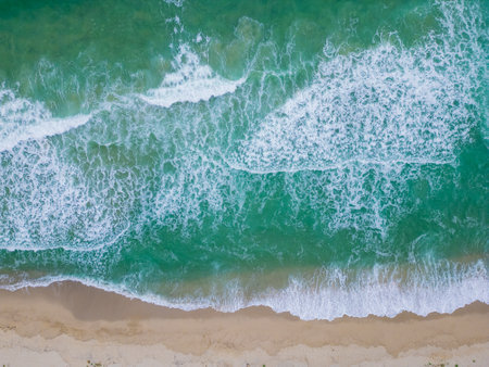 Gentle waves lapping against a sandy beach under bright sunlight in a coastal paradise during...