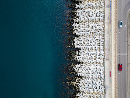 Heavy concrete tetrapods lined along the shoreline at a coastal area during daylight hoursの写真素材