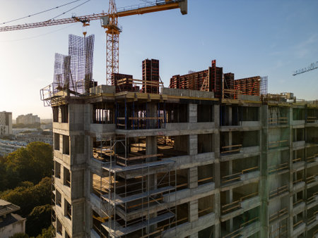 A drone video capturing the construction site of a high-rise building at sunset. The structures...