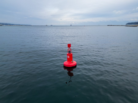 Close-up aerial view of a red navigation buoy floating in the calm waters of the Sea. The buoy ensures safe navigation and adds vibrant color to the maritime sceneの写真素材