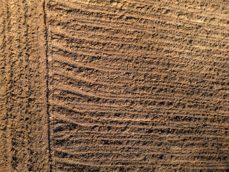 Freshly plowed soil with evenly spaced furrows, creating a textured pattern across the surface. The rich, earthy tones and straight lines reflect agricultural preparation and natural detailの写真素材