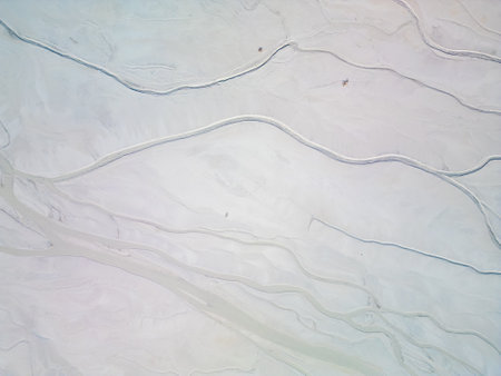 A turquoise pond near a cement factory, surrounded by rugged hills. The vivid water contrasts with the barren land, creating a striking yet industrial scene.の写真素材
