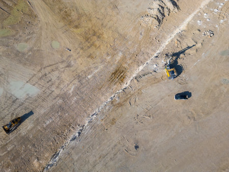 An open-pit quarry with terraced layers and heavy machinery operating on the dusty terrain. The industrial site highlights large-scale excavation processes and environmental transformationの写真素材