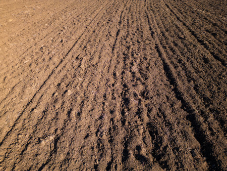 Freshly plowed soil with evenly spaced furrows, creating a textured pattern across the surface. The rich, earthy tones and straight lines reflect agricultural preparation and natural detailの写真素材