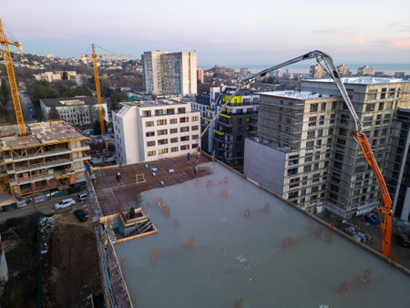 Aerial view of a construction site with a high-rise building under development. A concrete pump...