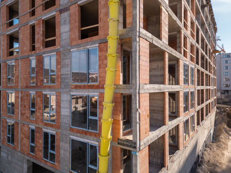Construction site of a high-rise building at sunny day. The structures concrete framework, cranes, and scaffolding are bathed in bright sunlight, highlighting urban developmentの写真素材