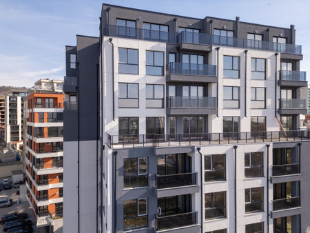 Aerial drone shot of a modern residential building facade with black panels and white balconies, highlighting clean architectural lines and contemporary urban designの写真素材