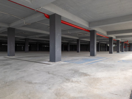 an empty underground parking garage with concrete pillars and open sides. The industrial space is illuminated by natural light, creating a modern yet abandoned atmosphereの写真素材