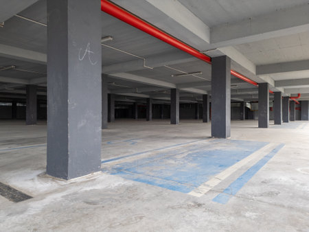 an empty underground parking garage with concrete pillars and open sides. The industrial space is illuminated by natural light, creating a modern yet abandoned atmosphereの写真素材