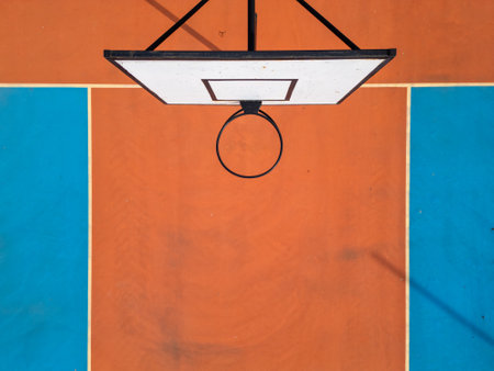 Aerial view of a basketball hoop and colorful court with vibrant orange and blue sections. The symmetrical layout and bold colors create a striking sports-themed compositionの写真素材