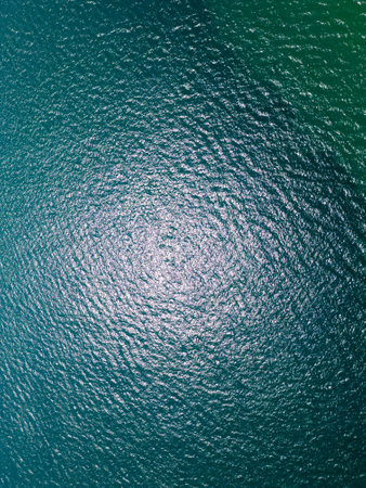 Aerial view of sun reflections on the surface of rippling turquoise sea water. Natural abstract background with glimmering ocean texture captured from aboveの写真素材