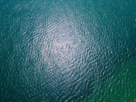 Aerial view of sun reflections on the surface of rippling turquoise sea water. Natural abstract background with glimmering ocean texture captured from aboveの写真素材