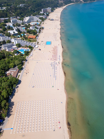 Aerial view of Albena resort on the Bulgarian Black Sea coast with wide sandy beach, umbrellas, hotels and forested hills in summerの写真素材