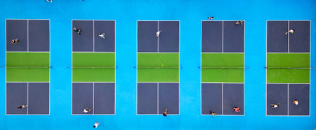 Aerial view of multiple pickleball courts with players in action. Colorful blue and green outdoor sports complex on a sunny day. Recreational activity and healthy lifestyle conceptの写真素材
