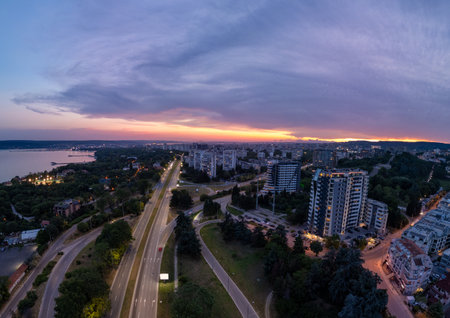 Aerial panoramic view of Varna, Bulgaria at sunset. Urban landscape with coastal city lights, residential buildings, highways, and dramatic sky over the Black Seaの写真素材