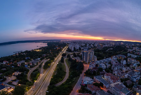Aerial panoramic view of Varna, Bulgaria at sunset. Urban landscape with coastal city lights, residential buildings, highways, and dramatic sky over the Black Seaの写真素材