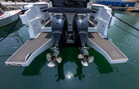Close-up view of a luxury boats twin outboard motors docked at marina. Clean, modern design with reflections on water and sunny weather.の写真素材
