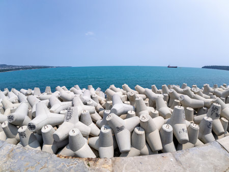 Close-up large concrete tetrapods stacked on a coastal breakwater. Designed to reduce wave impact and protect the shore. Industrial maritime infrastructure by the seaの写真素材