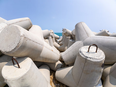 Close-up large concrete tetrapods stacked on a coastal breakwater. Designed to reduce wave impact and protect the shore. Industrial maritime infrastructure by the seaの写真素材