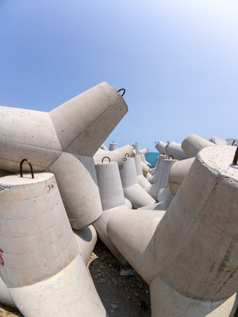 Close-up large concrete tetrapods stacked on a coastal breakwater. Designed to reduce wave impact and protect the shore. Industrial maritime infrastructure by the seaの写真素材