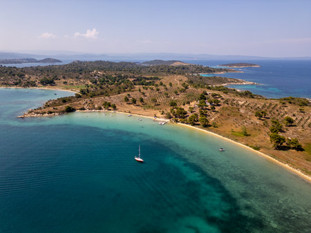 Aerial view of a scenic Mediterranean coastline with turquoise waters, sandy beaches, olive groves, and boats anchored near the shore on a sunny summer dayの写真素材