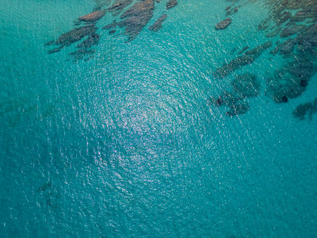 Aerial view of shimmering turquoise sea with underwater rocks visible through clear water. Peaceful surface reflecting sunlight on a calm summer day.の写真素材