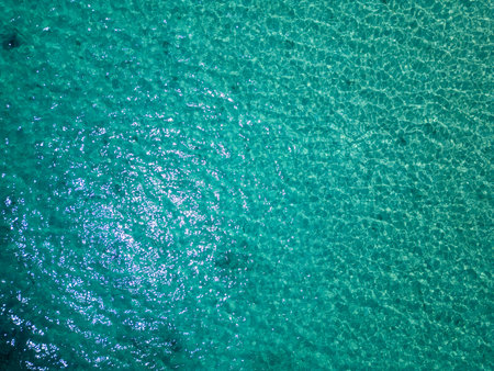 Aerial view of shimmering turquoise sea with underwater rocks visible through clear water. Peaceful surface reflecting sunlight on a calm summer dayの写真素材