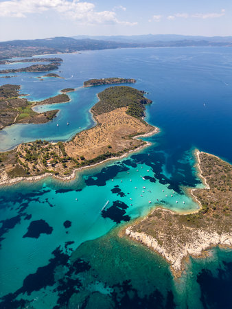 Aerial view of a stunning turquoise bay filled with anchored boats near a scenic Mediterranean coastline with olive groves and clear water, captured on a bright summer dayの写真素材