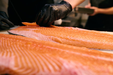 Chef slicing fresh salmon fillet with precision on a cutting board in a professional kitchen....