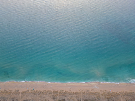 Top-down aerial view of wild beach with turquoise sea and soft waves. Peaceful coastal landscape, minimalistic natural textures and serene atmosphere. Ideal for background or transition footageの写真素材