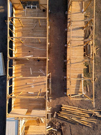 Aerial view of wooden house construction in progress. Framework and walls being built with timber, showing structure and building processの写真素材