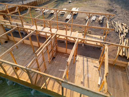 Aerial view of wooden house construction in progress. Framework and walls being built with timber, showing structure and building processの写真素材